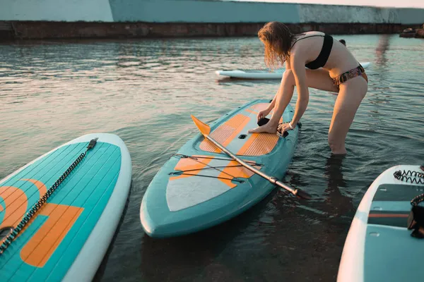 Atletische vrouw peddelen op een SUP zit paddle board in blauw water zee op zomerdag — Stockfoto