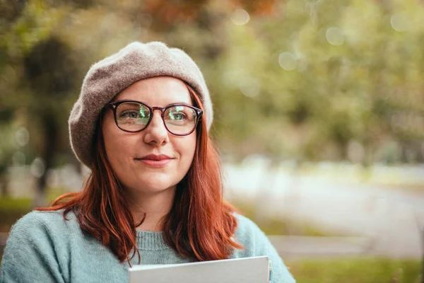 Estudante feminina alegre em óculos olha para a câmera no parque — Fotografia de Stock
