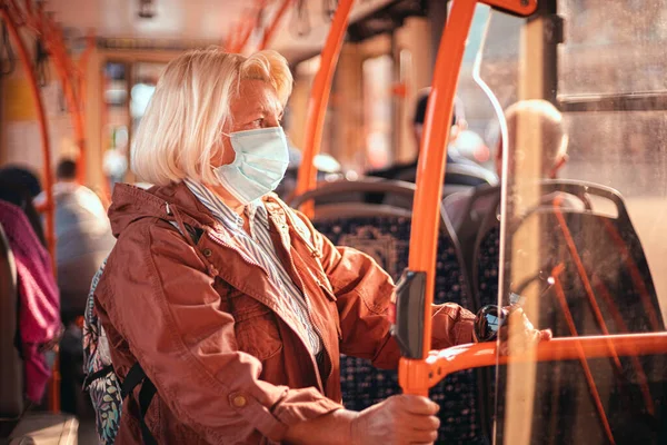Érett nő, sebészeti védőmaszkot visel a tömegközlekedésben — Stock Fotó