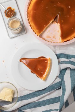 Klasik cheesecake dilimleri, beyaz tabakta karamel soslu gri çimento arka planda. Metin için alanı kopyala.