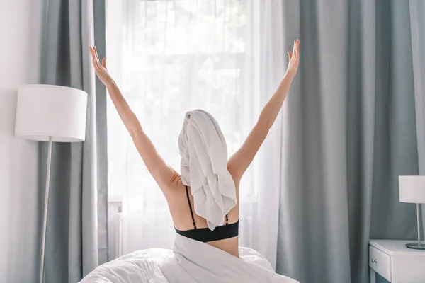 一个漂亮的女人 穿着白色的毯子 在床上享受着早晨的惬意 女人醒来后躺在舒适舒适的床上 开始新的一天 — 图库照片