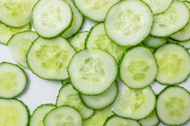 Arka planda bir sürü yuvarlak dilimleri olan taze salatalık..