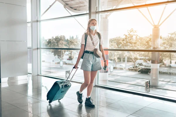 Blond haar vrouwelijke toeristische hand met paspoort met koffer bagage wachtruimte van de luchthaven terminal voor een reis. Reizen na Covid-19 pandemie — Stockfoto