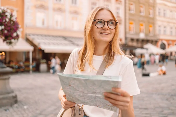 Mujer joven enfocada con un mapa de la ciudad viajando en una calle de la ciudad, viajando en Europa, libertad y estilo de vida activo — Foto de Stock