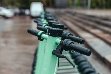 Yağmurlu şehrin göbeğinde yeşil naneli, motorlu scooter 'lar. Elektrik Şehir Taşımacılığı Konsepti.