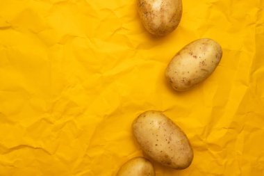 Renkli sarı arka planda doğal patatesler. Sebzeler, en üst görünüm düz.