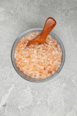 Pembe Himalaya tuzu ve gri masa arkasında tahta kaşık. Üst görünüm, düz görünüm, kopyalama alanı.