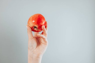 El ele tutuşan kırmızı elma, gri arka planda izole edilmiş..