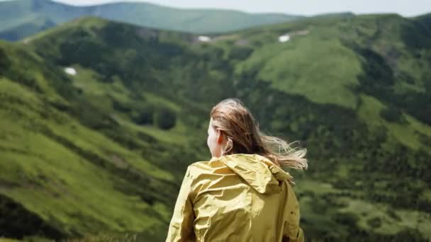 迷人的快乐的女徒步旅行者 她的头发在风中飘扬 俯瞰着山顶的美景 夏天阳光明媚的日子里望着高山谷地的女人 — 图库视频影像