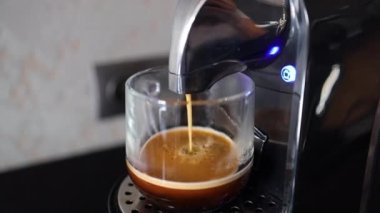 Mutfaktaki masada şeffaf cam bardağı olan modern kahve makinesi. Kahve espresso dolduruyorum.