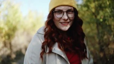 Genç mutlu hippi kadın, günbatımı ışınlarının arka planında dans ediyor. Kıvırcık kıvırcık renkli saçlar rüzgarda yavaş çekimde