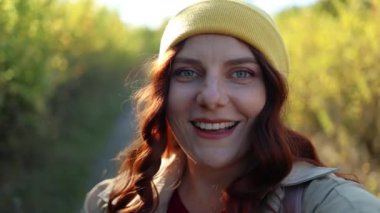 Kafkas neşeli gülümseyen güzel genç bir kadın sonbahar parkının dışında blog için video kaydediyor.