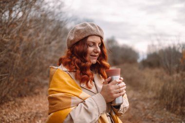 Sıcak içecekli termos. Seyahat kupası tutan mutlu kıvırcık saçlı kadın ya da yürüyen çelik termo şişe. Sıfır atık eko kavramı