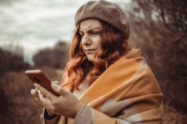 Güz sokağında cep telefonu sorunları olan kafası karışmış kızgın bir kadın.