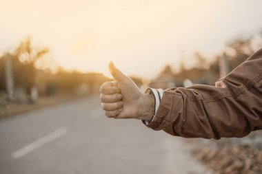 Kadın eli ve otostop işareti şehirde otostop ile seyahat ediyor. Kadın arabayı durdurmayı deniyor. Macera ve turizm konsepti.