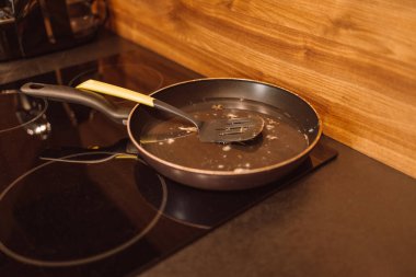Modern bir mutfakta plastik spatulayla pişirilmiş kirli kızartma tavası.