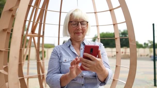 Okostelefonos nő sms-ezik az alkalmazással okostelefonon. 5G technológia eszköz szabadban — Stock videók
