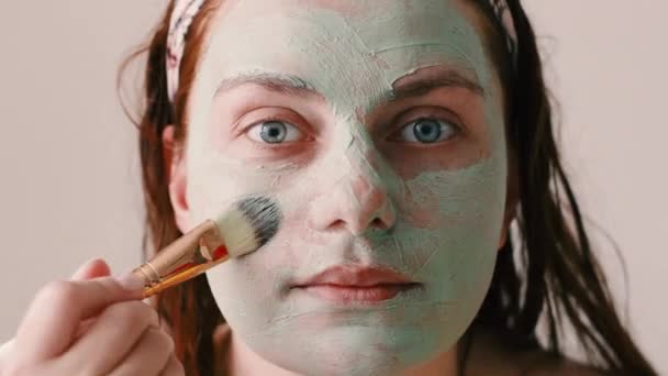 Zbliż portret kobiety zakładającej kosmetyczną maskę do twarzy w łazience. Pielęgnacja i leczenie skóry, spa, naturalne piękno i koncepcja kosmetologii. — Wideo stockowe