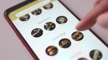 Akıllı telefondan fast food siparişi vermek. Bir kadın yemek teslimat uygulamasını kullanarak sipariş veriyor. Ekran bulanıklaştı.