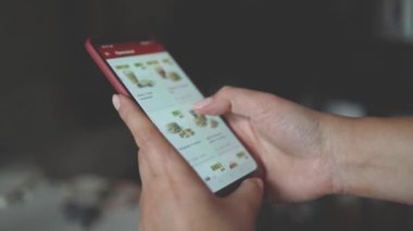 Telefonunu online gıda dağıtım pazarı üzerinden kullanıyor. Sipariş edilecek yiyecek listesi olan bir internet mağaza yazılımı. Eline odaklan.