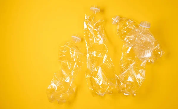 在黄色背景上使用皱巴巴的塑料瓶 生态问题 顶部视图 复制空间 — 图库照片