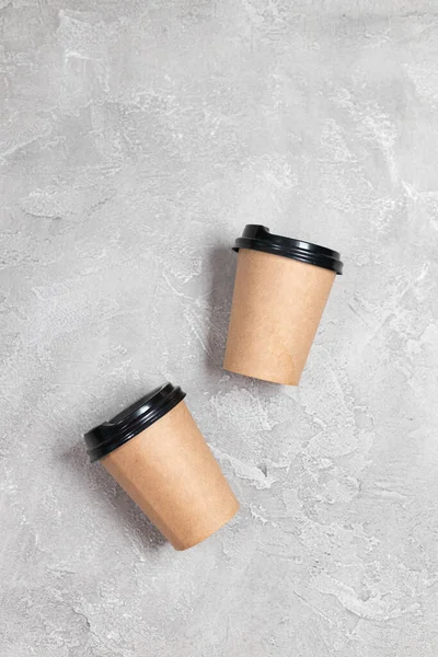 Dos tazas de papel kraft café maqueta sobre un fondo de hormigón gris. — Foto de Stock