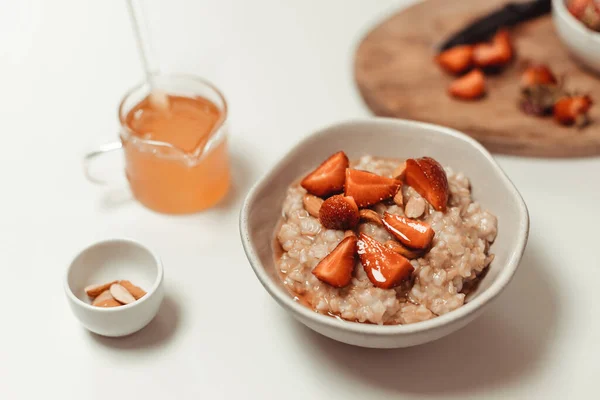 碗燕麦粥 桌上放草莓片和杏仁片 健康的生活方式 健康的饮食 — 图库照片