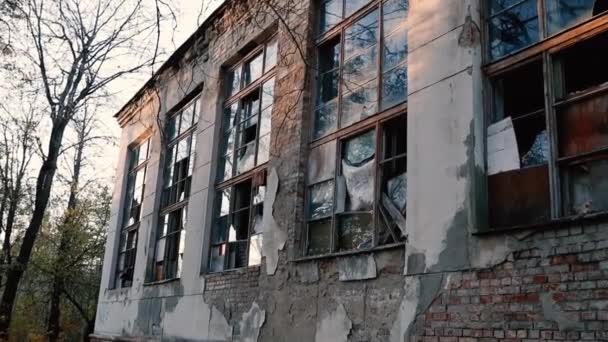 Fachada de ladrillo de un antiguo edificio abandonado con ventanas en los rayos del sol — Vídeo de stock