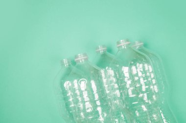 Kullanılan plastik şişelerin üst görünümü geri dönüşüm için yeşil arka planda kaotik bir şekilde yatar. Üst görünüm, alanı kopyala.