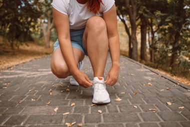 Spor koşucusu kadınların spor yaparken, spor yaparken, spor yaparken ve sağlıklı bir yaşam sürerken beyaz spor ayakkabılarını bağlarken çekilmiş görüntüsü.
