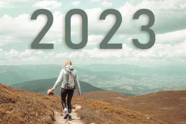 Yeni yıl konsepti 2023. Dağın tepesinde yürüyüş yapan kadın.