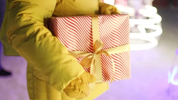 Female hands holding gift present box standing on night street. Xmas garland decoration. Christmas and New Year shopping, sale concept — Wideo stockowe