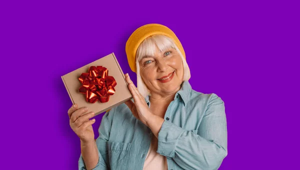 Portrait of attractive romance 50s woman hands holding gift good mood isolated over bright purple color background — Fotografia de Stock