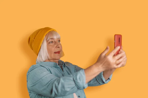 Adult beautiful woman in stylish clothes taking a selfie posing isolated on yellow orange background — Fotografia de Stock