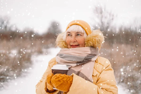 40s 50 femme en jaune vêtements d'hiver détient café chaud ou thé boisson de tasse en papier à l'extérieur dans le parc d'hiver — Photo