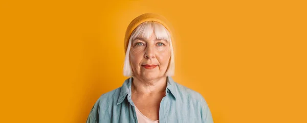 Hermosa mujer de los años 50 con cabello rubio en ropa casual con estilo con copyspace mirando a la cámara en color amarillo retrato de estudio de fondo. — Foto de Stock