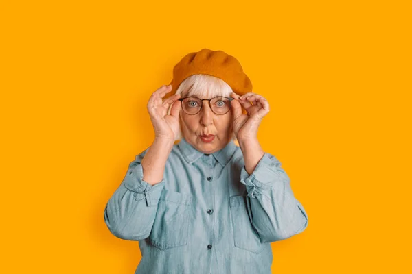Photo of blonde hair 50s woman astonished face touch glasses look camera isolated over orange color background — Fotografia de Stock
