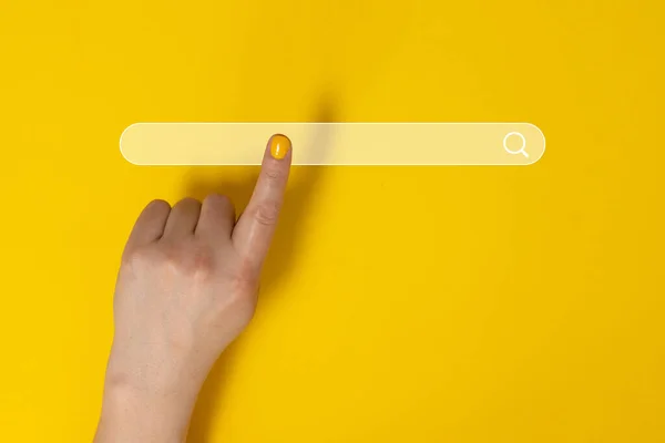 Жінка вказує на щось на жовтому тлі, крупним планом. Пальці торкаються кнопки пошуку зі збільшувальним склом — стокове фото