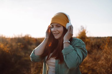 30 'lu yaşlarda, kulaklık takmış, müzik dinleyen, çayırda müzik dinlemeyi seven beyaz bir kadın.