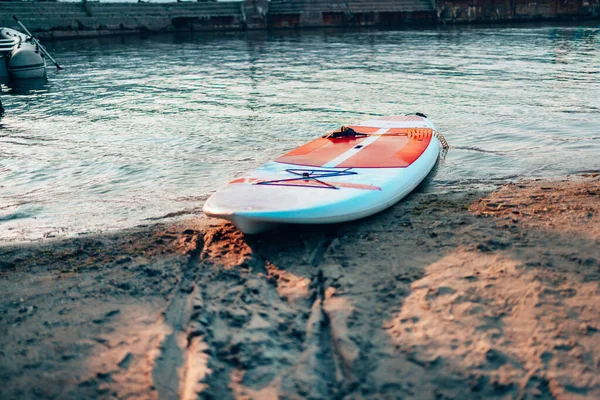 Aproape de stand up SUP paddle board pe lac sau mare cu crini de apă albastră, vâslind în timpul verii la apus de soare. Vacanță de vară — Fotografie, imagine de stoc