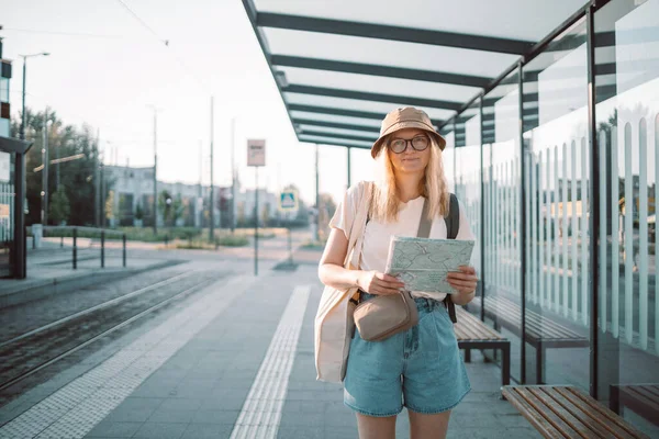 Νεαρή τουρίστρια γυναίκα χέρι χάρτη σε εξωτερικούς χώρους στη στάση του λεωφορείου σε ένα δρόμο της πόλης, που ταξιδεύουν στην Ευρώπη. Τουρισμός, έννοια προορισμού — Φωτογραφία Αρχείου