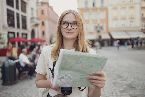 Mujer joven y feliz usando el mapa de la ciudad en una calle de la ciudad, viajando por Europa, libertad y estilo de vida activo — Foto de Stock