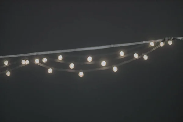 Garland with small led lamps shining on black background. — Stock Photo, Image