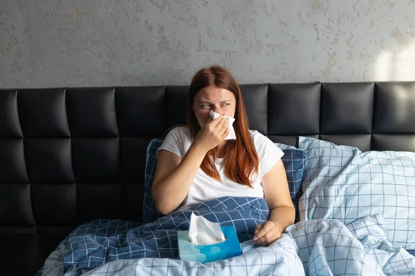 Coronavirus infeliz mujer estresada con pañuelo secreción nasal infección por resfriado en camiseta blanca sentado en la cama en la cama en casa. —  Fotos de Stock
