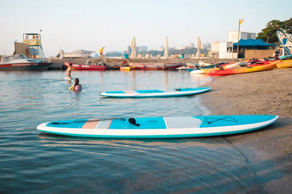 Primer plano de stand up SUP paddle board en el lago o el mar con lirios de agua azul, remando en verano al atardecer. Vacaciones familiares de verano — Foto de Stock