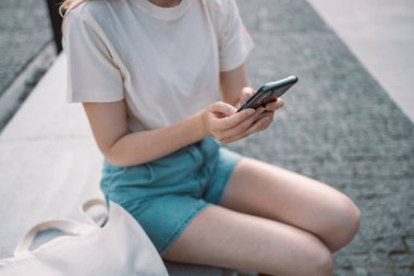 Woman hands using smart phone texting online on dating app holding cellphone mobile phone outside walking sunny summer day while travel vacation