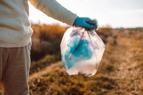 地球の日だ 自然の純粋さ ゴム手袋を手にした女性清掃ボランティア活動家がゴミ袋にビニール袋のゴミを入れ ゴミを集める — ストック写真