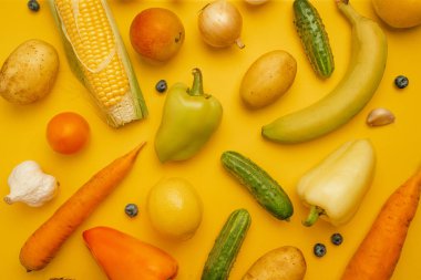 Sarı arka planda çeşitli abur cubur ve tatlılar. Üst manzara, düz yatış. Tatlı, tatlı, diyet konsepti.