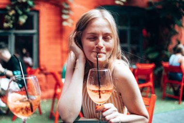30 'lu yaşlardaki kadınlar restoranın arka planında bir bardak soğuk kokteyl Aperol spreyiyle eğleniyorlar..