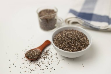 Tahta kaşık ve fincandan Chia tohumları beyaz arkaplanlı, kopya alanı olan, yukarıdan görünüm